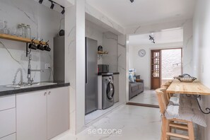 Eine moderne Küche mit einem Edelstahl-Kühlschrank, einer Waschmaschine und einem Holzespeisesaal mit gestreiftem Tischlein.