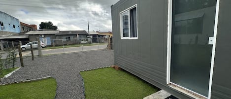 A modern building with a large window and a small lawn area.
