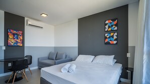 Ein modernes Hotelzimmer mit einem Bett, einem Schreibtisch, einem Stuhl und zwei abstrakten Bildern an den Wänden.