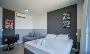Ein modernes Hotelzimmer mit einem Bett, einem Schreibtisch, einem Stuhl und zwei abstrakten Bildern an den Wänden.