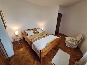 Una camera da letto con un letto in legno, due lampade sui comodini, una sedia e un tavolino.