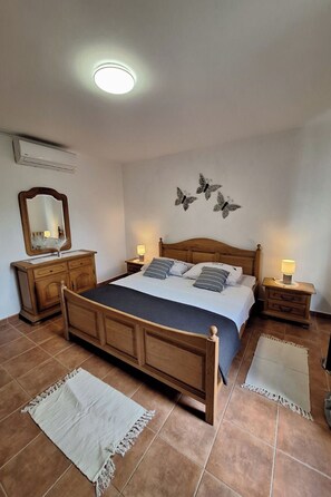 Een slaapkamer met een houten bed, twee nachtkastjes met lampen, een spiegel en decoratieve vlinderkunst aan de wand.