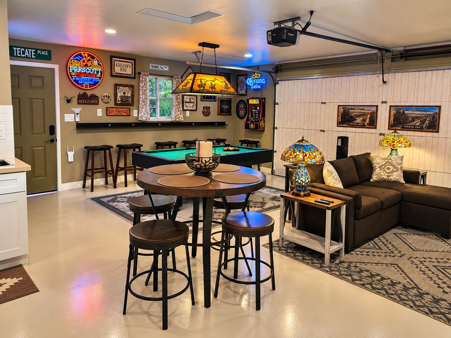 Un espace bar avec une table de billard, des tabourets et un panneau lumineux au néon.