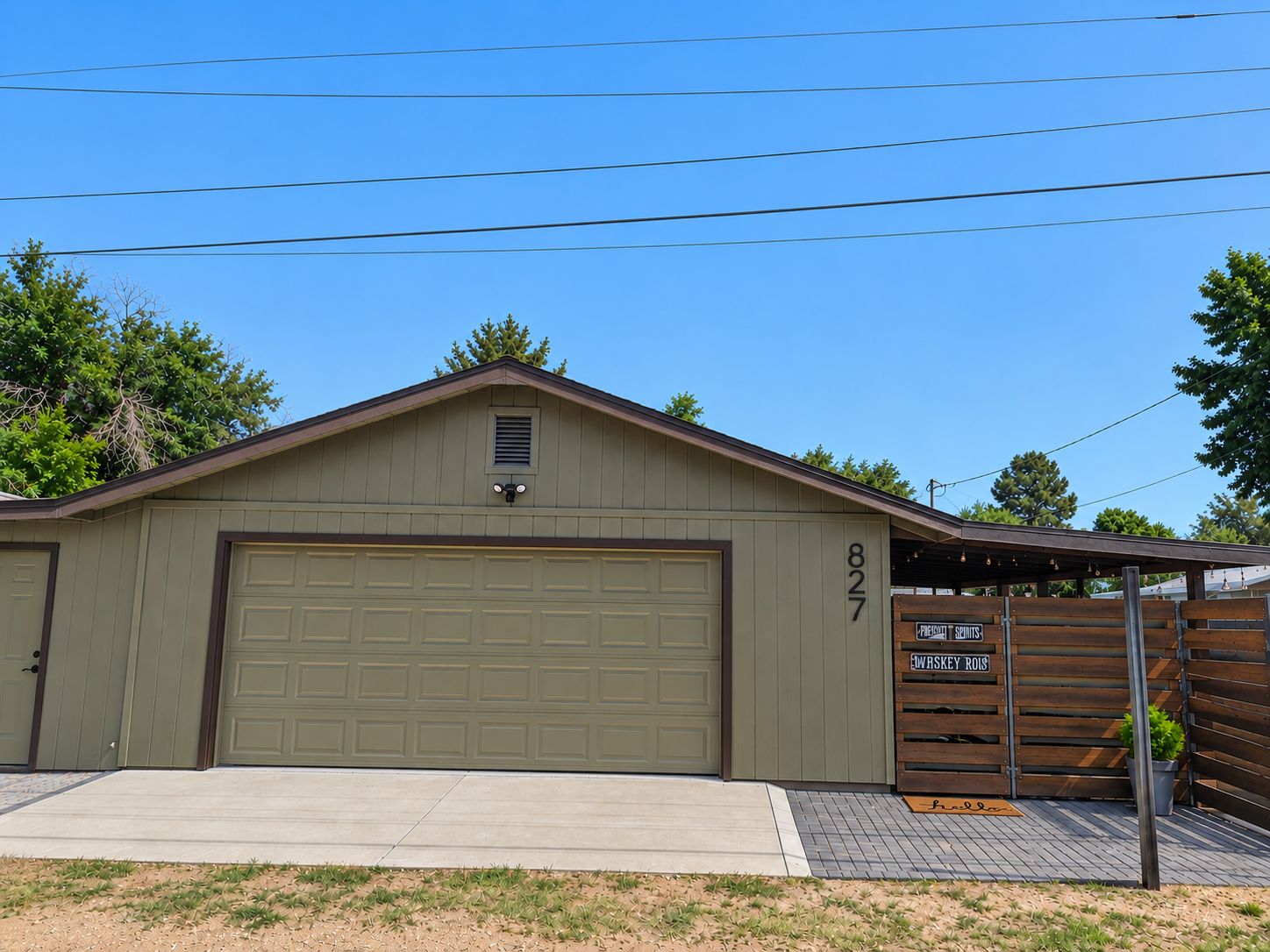 A single-story building with a garage door, a small window, and a wooden fence with signs.