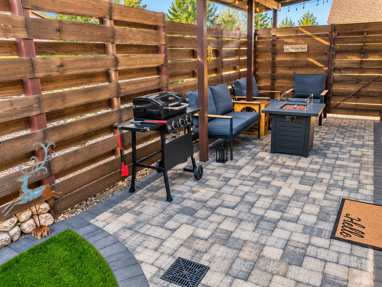 Un patio al aire libre con una parrilla, zona de estar y valla de madera.