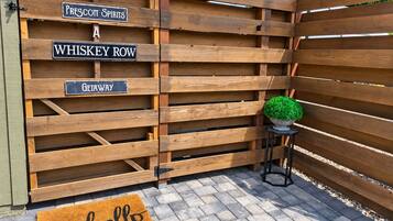 Een houten poort met borden voor 'Prescott Spirits', 'Whiskey Row' en 'Getaway'. Een bloempot en een deurmat met de tekst 'hello' zijn ook zichtbaar.