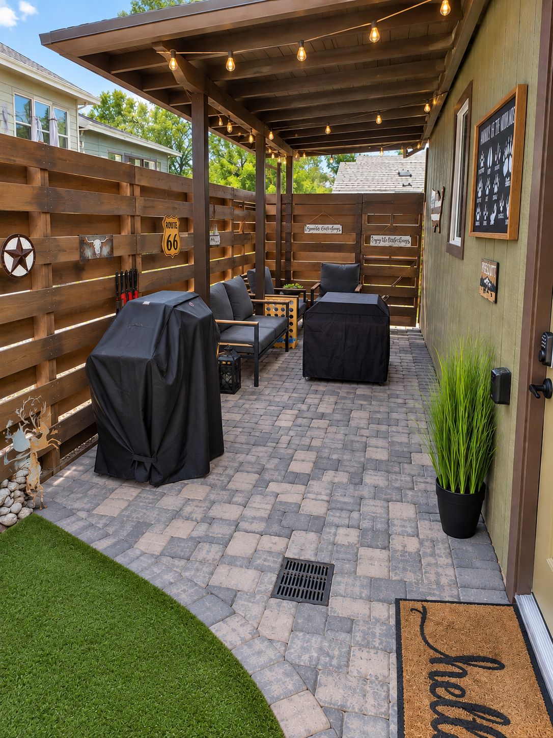 An outdoor patio with a covered seating area, a barbecue grill, and a decorative fence.