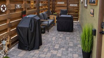 An outdoor patio with a covered seating area, a barbecue grill, and a decorative fence.