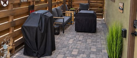 An outdoor patio with a covered seating area, a barbecue grill, and a decorative fence.