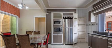 Una cocina moderna con electrodomésticos integrados, un comedor con mesa y sillas, y una araña.