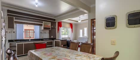 Comedor con una mesa dispuesta para cuatro personas, cocina con electrodomésticos modernos y vistas al exterior a través de una ventana.