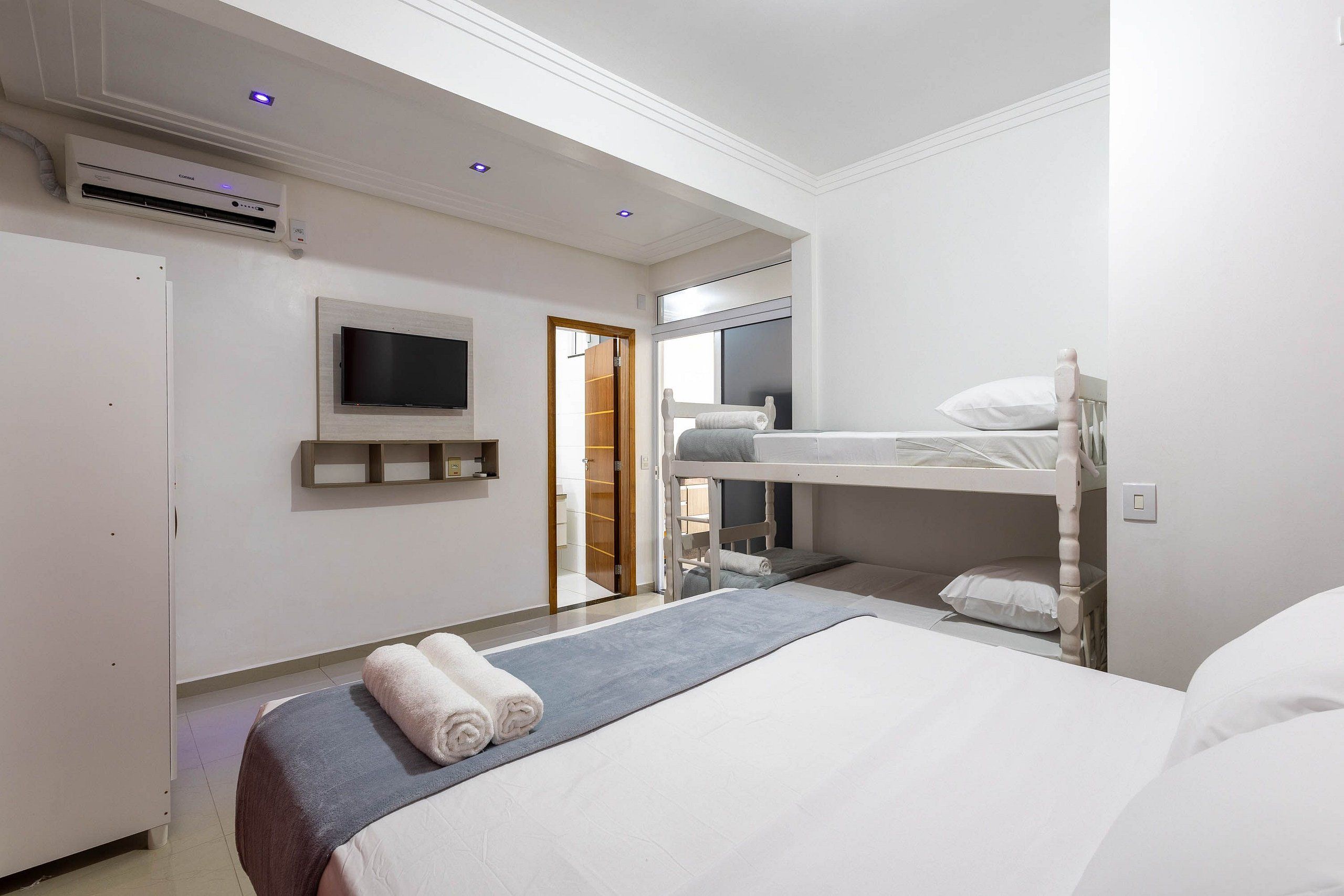 Une chambre d’hôtel équipée d’un lit superposé, d’un téléviseur à écran plat fixé au mur et d’un appareil de climatisation.