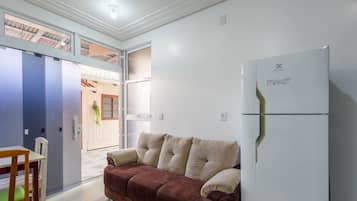 A compact living space with a kitchenette, a sofa, a dining table, and a refrigerator.
