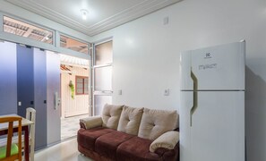 Um espaço compacto com cozinha compacta, sofá, mesa de jantar e geladeira.