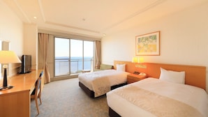 A hotel room with two beds, a desk, a TV, and a large window with a view. - KKR Hotel Atami (Atami)