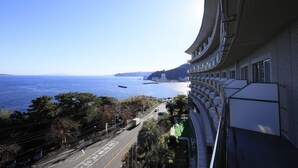 Un hotel frente al mar, con fachada curva y una carretera con vehículos.