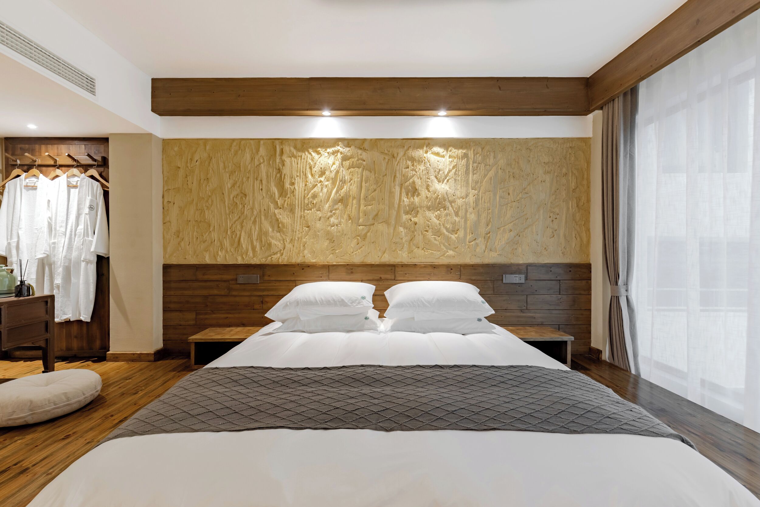 A bedroom with a large bed, wooden headboard, and a wardrobe with hanging clothes.