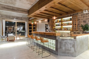 A bar area with a stone wall, wooden ceiling, and a bar counter with stools. - Mount Huangshan Wen'an B&B (Huangshan)