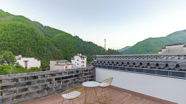A rooftop terrace with a table and two chairs, overlooking a forested hillside. - Mount Huangshan Wen'an B&B (Huangshan)