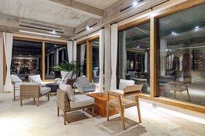 A modern interior with large windows, wicker furniture, and a view of the outside.