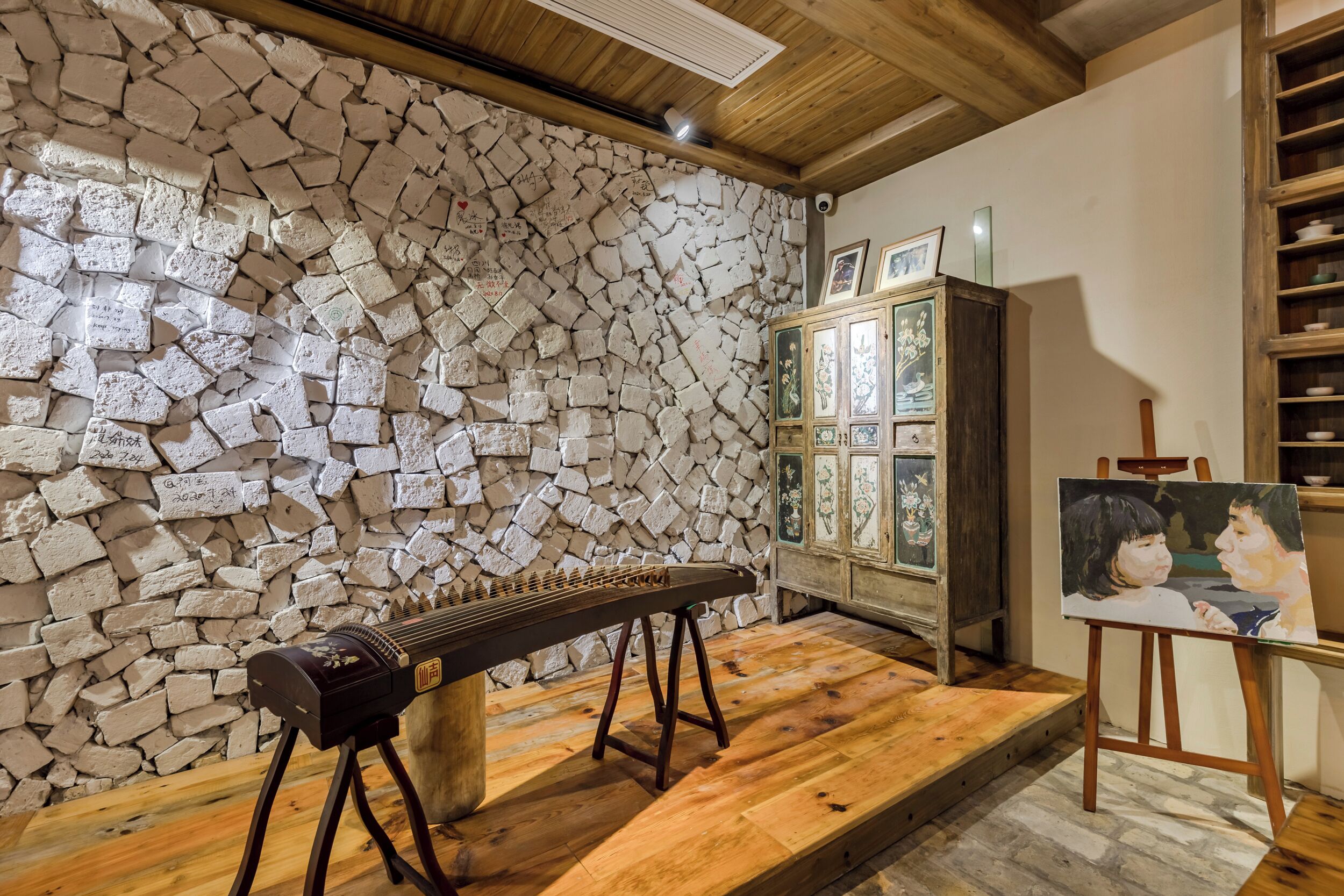 A room with a stone wall, wooden cabinet, and a musical instrument.