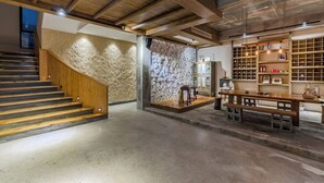A spacious interior with a wooden staircase, a stone wall, and a wooden bench area. - Mount Huangshan Wen'an B&B (Huangshan)