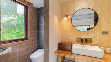 Un baño moderno con tocador de madera, lavamanos blanco y un espejo grande.