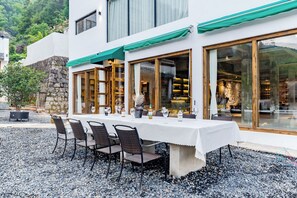 An outdoor dining area with a table set for four, surrounded by chairs, and a view of the interior through large windows. - Mount Huangshan Wen'an B&B (Huangshan)