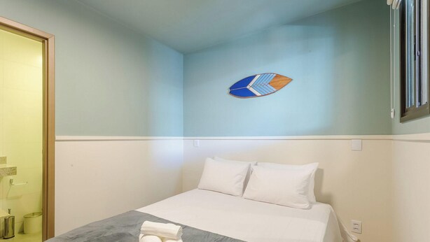 Habitación de hotel con cama, toalla, decoración en la pared y ventana.