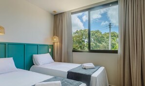 A hotel room with two beds, a teal headboard, a large window with curtains, and a view of trees and power lines. - Apt 350m From the Beach in Condo w/ Pool Bbc0102 (Maraú)
