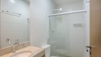 Un baño con lavamanos, inodoro y ducha con mampara de vidrio.