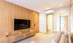 A modern living room with a wooden wall, a flat-screen TV, a sofa, and a door leading to a bathroom. - Modern apt w/ 3 Suites 350m From the Beach Bbc0004 (Maraú)
