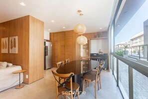 A modern kitchen with a large island, wooden cabinets, and a dining area with a round table and chairs. - Modern apt w/ 3 Suites 350m From the Beach Bbc0004 (Maraú)