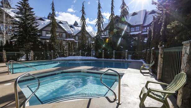 A pool with metal railings and a chair, surrounded by trees and buildings. - Modern Whistler Stay | Full Kitchen & Fireplace for Cozy Nights (Squamish-Lillooet)