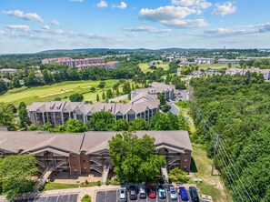 Ein mehrstöckiges Hotel mit Parkplatz und einem Golfplatz im Hintergrund.