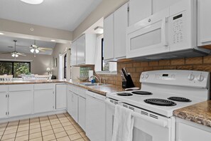 A modern kitchen with white cabinetry, a built-in oven, and a granite countertop. - 2BR/2BA Branson condo with king beds, pool, hot tub, and balcony. (Branson)