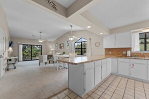 A spacious kitchen with a large island, white cabinetry, and a dining area with chairs and a table. - 2BR/2BA Branson condo with king beds, pool, hot tub, and balcony. (Branson)