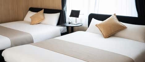 Habitación de hotel con dos camas, una mesita y un ventanal con cortinas.