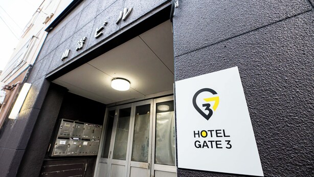 Entrada de un hotel con un letrero que dice 'HOTEL GATE 3' y un logotipo sobre la entrada.