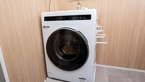 Una lavadora de carga frontal en una habitación con paredes de madera y piso de baldosas.