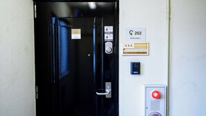 Puerta negra de una habitación de hotel con lector de tarjetas, teclado digital y sistema de intercomunicador instalado en la pared.