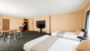 Habitación de hotel con dos camas, un escritorio, una silla, un televisor y un armario.