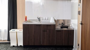 Una kitchenette compacta con horno integrado, cafetera y un refrigerador pequeño.