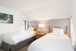 Ein Zimmer mit zwei Betten, einem Nachttisch mit Lampe und einem Gemälde an der Wand.
