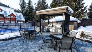 Een terras buiten met een barbecueplaats, een zwembad en een overdekte zithoek.