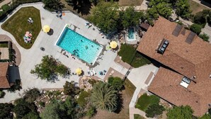 Eine Luftaufnahme eines Wohngebiets mit einem rechteckigen Swimmingpool, umgeben von einer gepflasterten Terrasse.