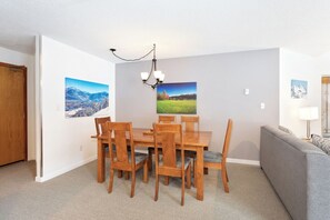 A dining area with a wooden table and chairs, a chandelier, and two wall-mounted pictures. - Whistler Escape | Spacious Oasis w/ Mountain Views | Winter Outdoors (Whistler)