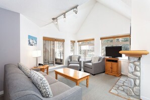 A living room with a sofa, armchairs, a coffee table, a fireplace, and a television. - Whistler Escape | Spacious Oasis w/ Mountain Views | Winter Outdoors (Whistler)