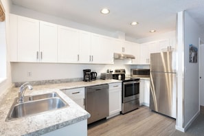 A modern kitchen with white cabinets, stainless steel appliances, and a granite countertop. - Whistler Escape | Spacious Oasis w/ Mountain Views | Winter Outdoors (Whistler)