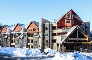 A multi-story hotel with a ski lodge entrance, balconies, and a snow-covered ground. - Whistler Creekside Stay | Modern Kitchen & Scenic Views | Near Gondola (Whistler)